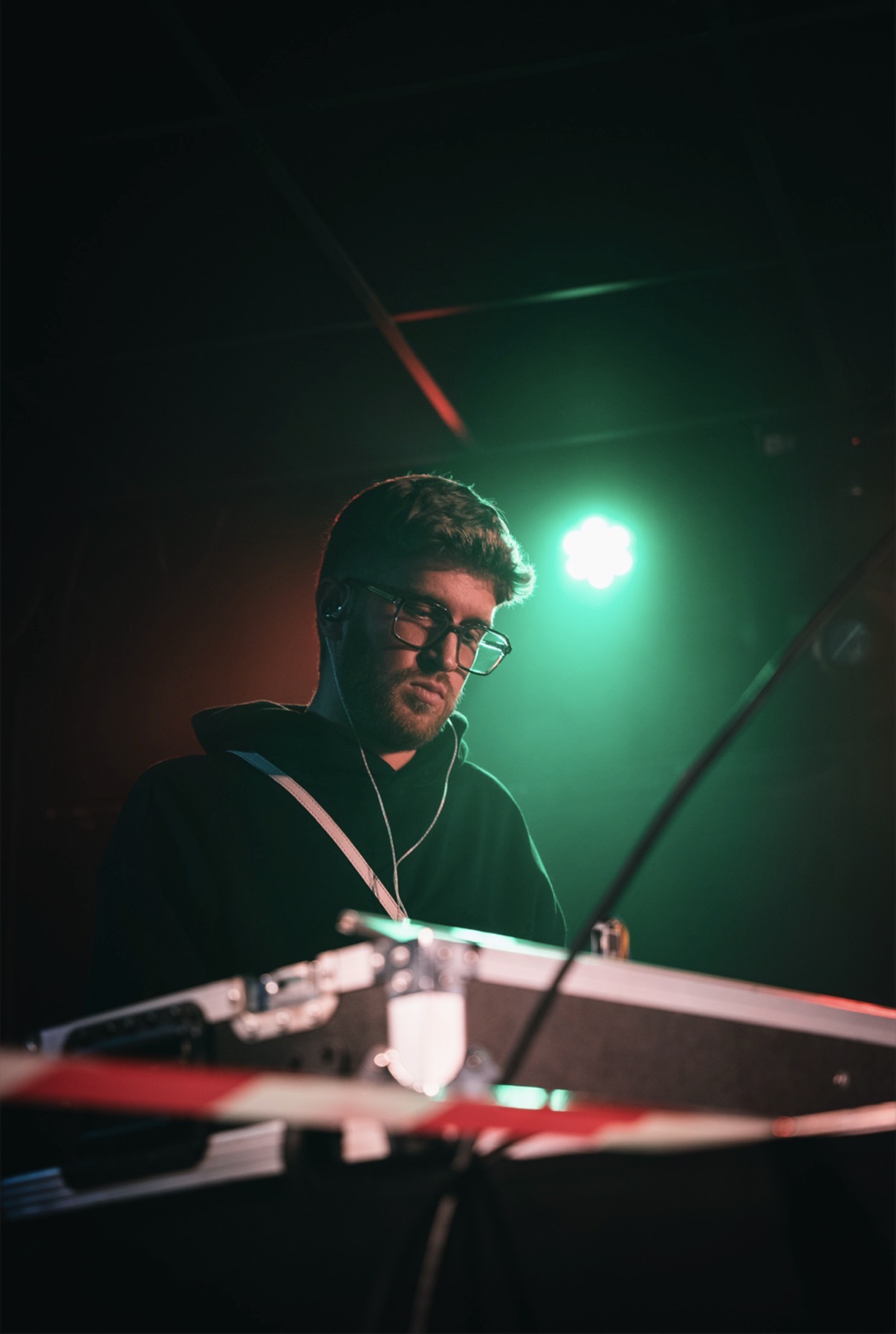 Een dj achter de draaitafels in groen podiumlicht
