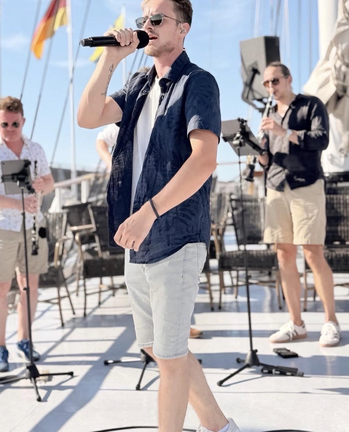 Een artiest met microfoon treedt op aan boord, met de orkestmusici achter hem